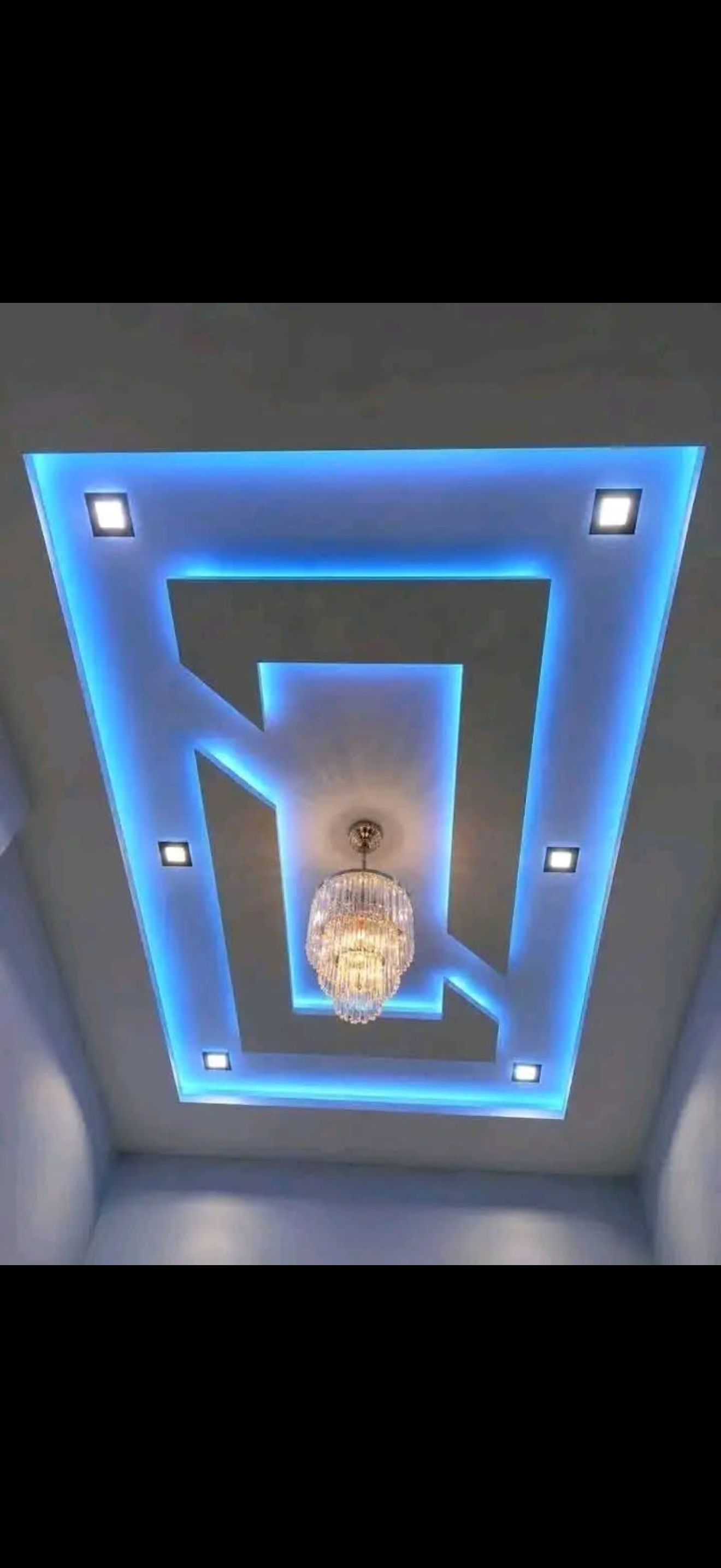 Rectangular drywall ceiling with blue LED cove lighting, square recessed spotlights and a crystal chandelier