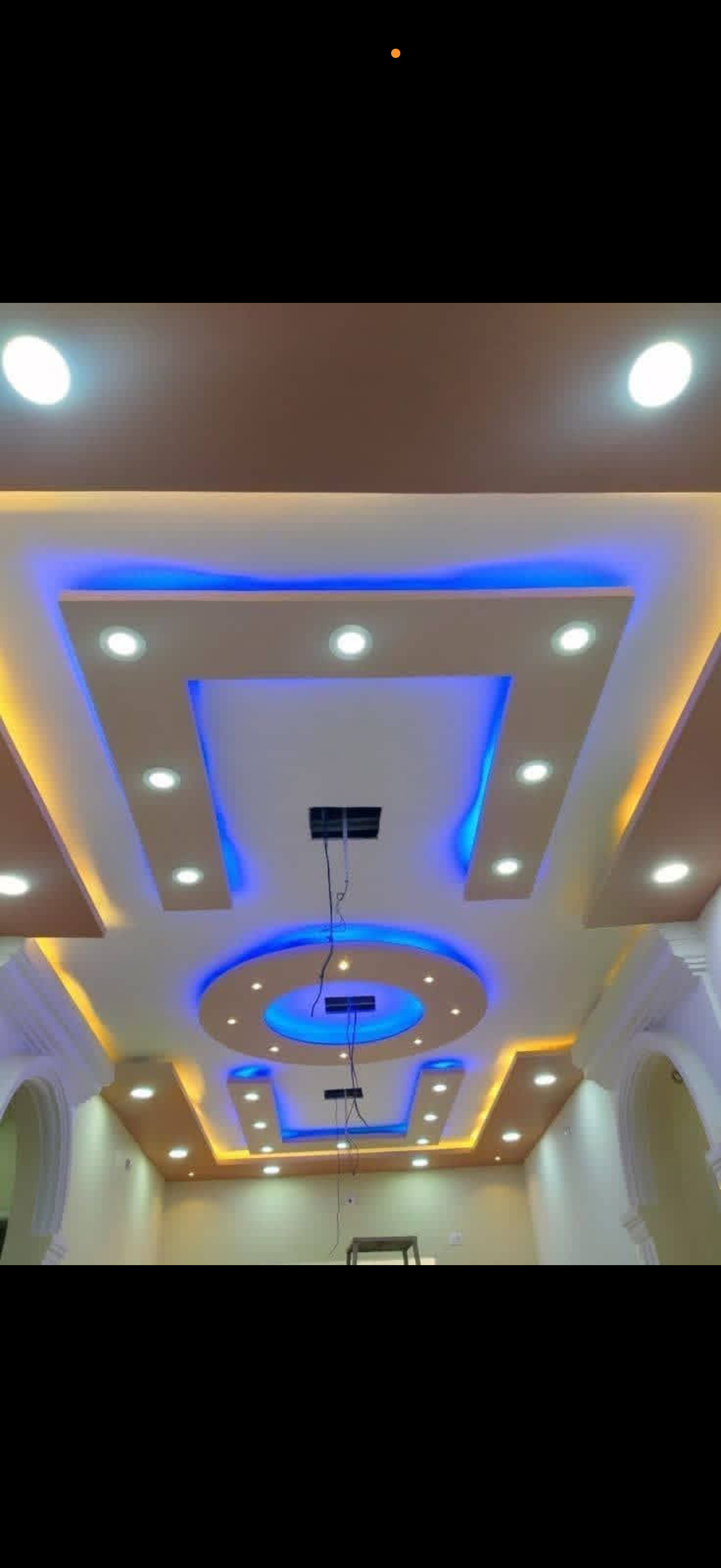 Geometric white drywall ceiling with blue LED accent lighting, a central oval medallion and recessed spotlights