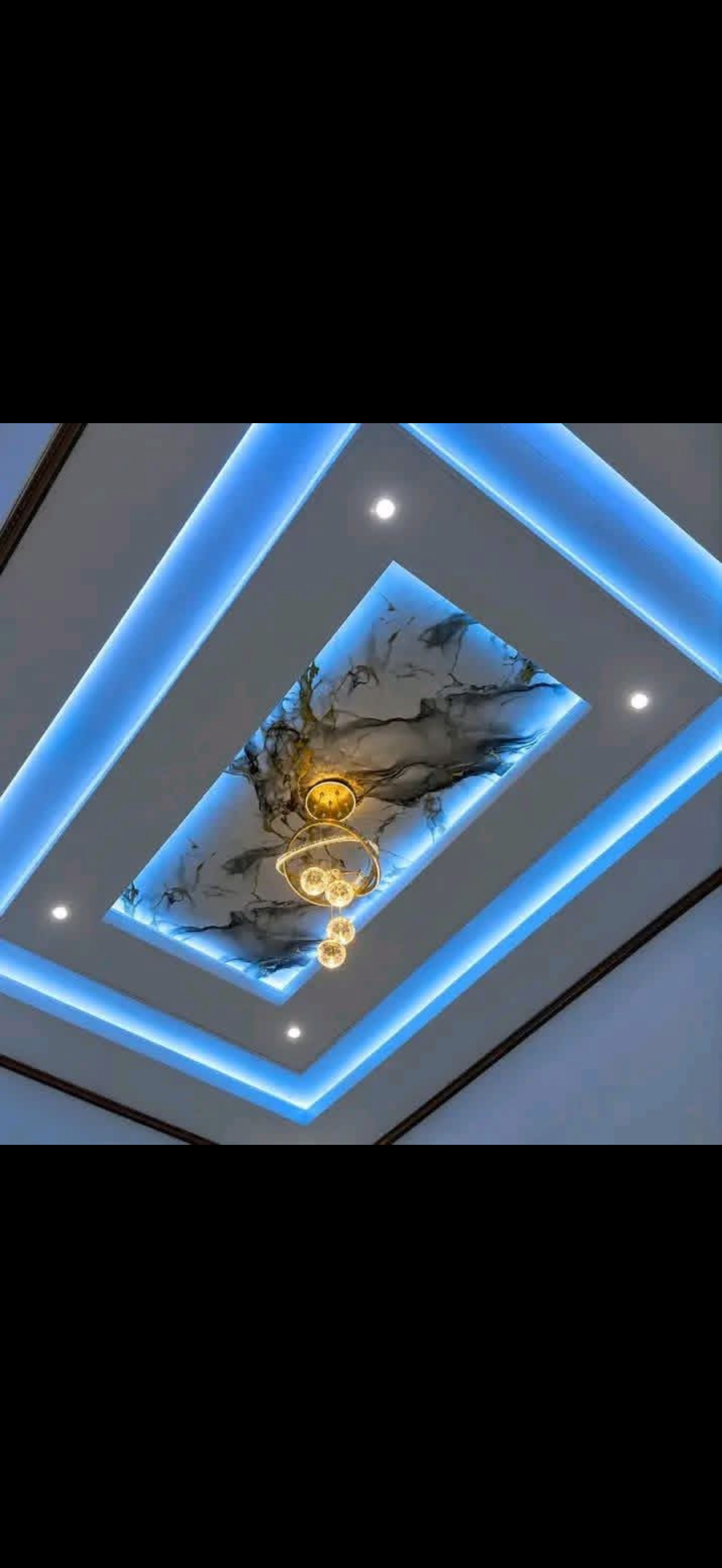 Drywall ceiling with blue LED cove lighting framing a marble-print center panel and a gold crystal chandelier