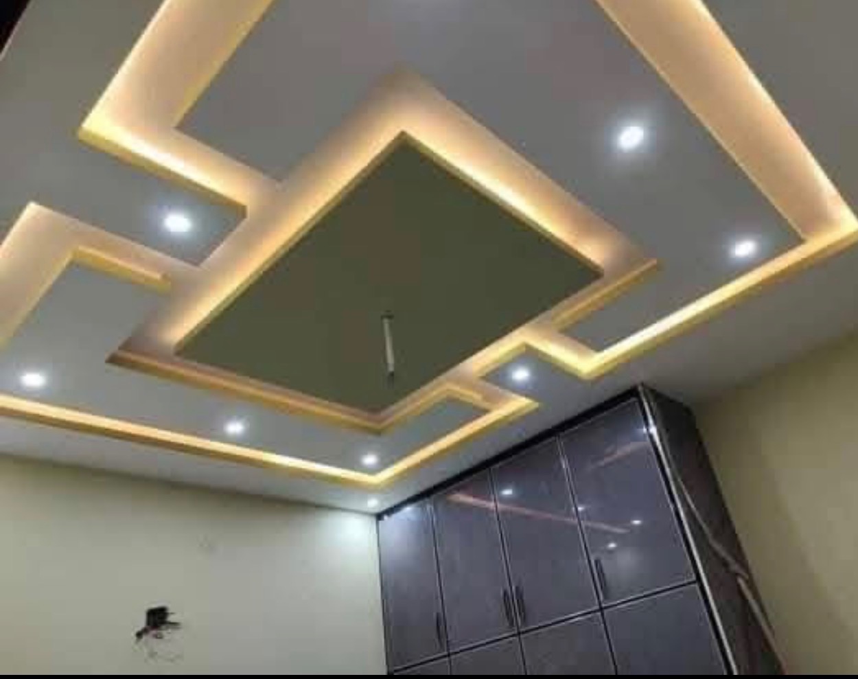 Layered stepped drywall tray ceiling with warm gold cove lighting above dark cabinetry