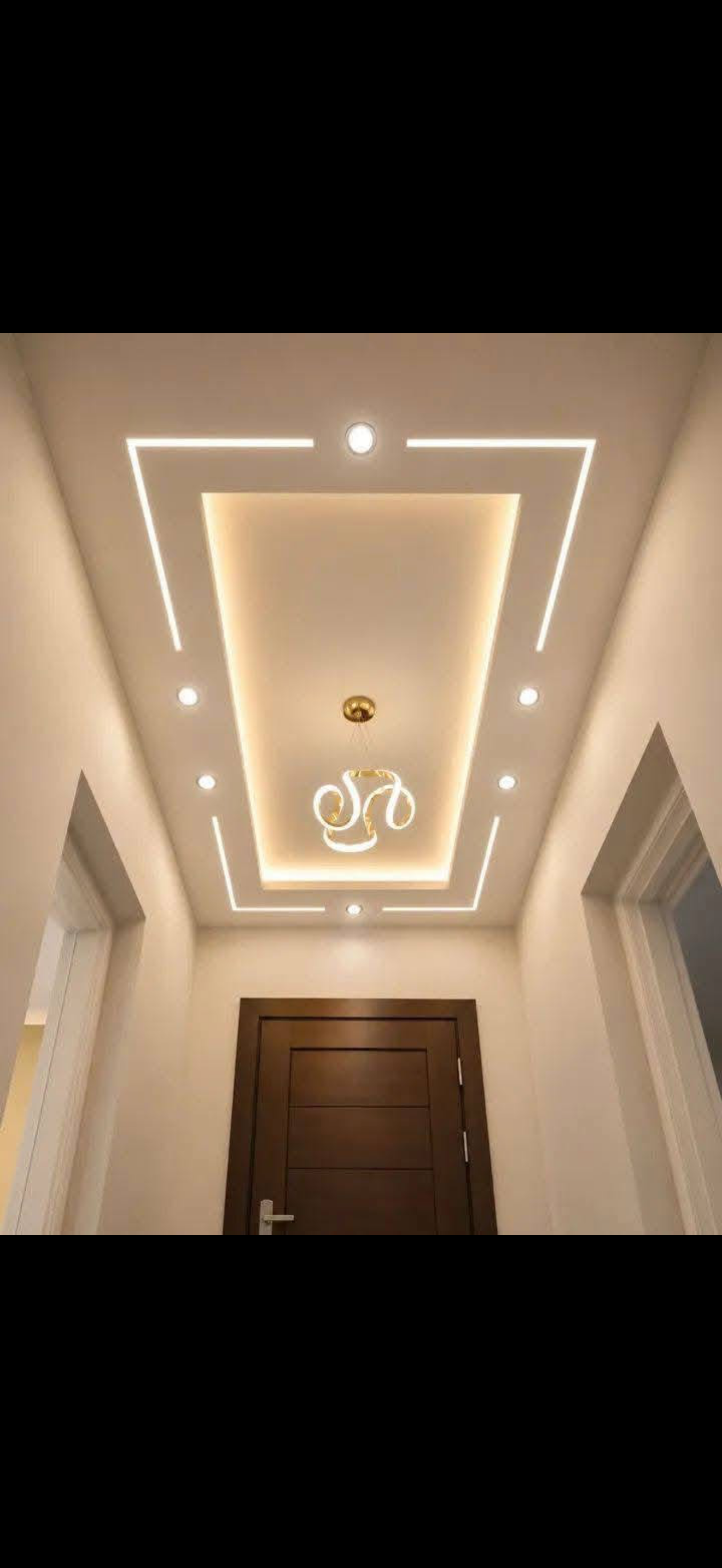 Entry hallway with a trapezoid drywall ceiling design outlined by warm LED lines and a decorative pendant above a wood door