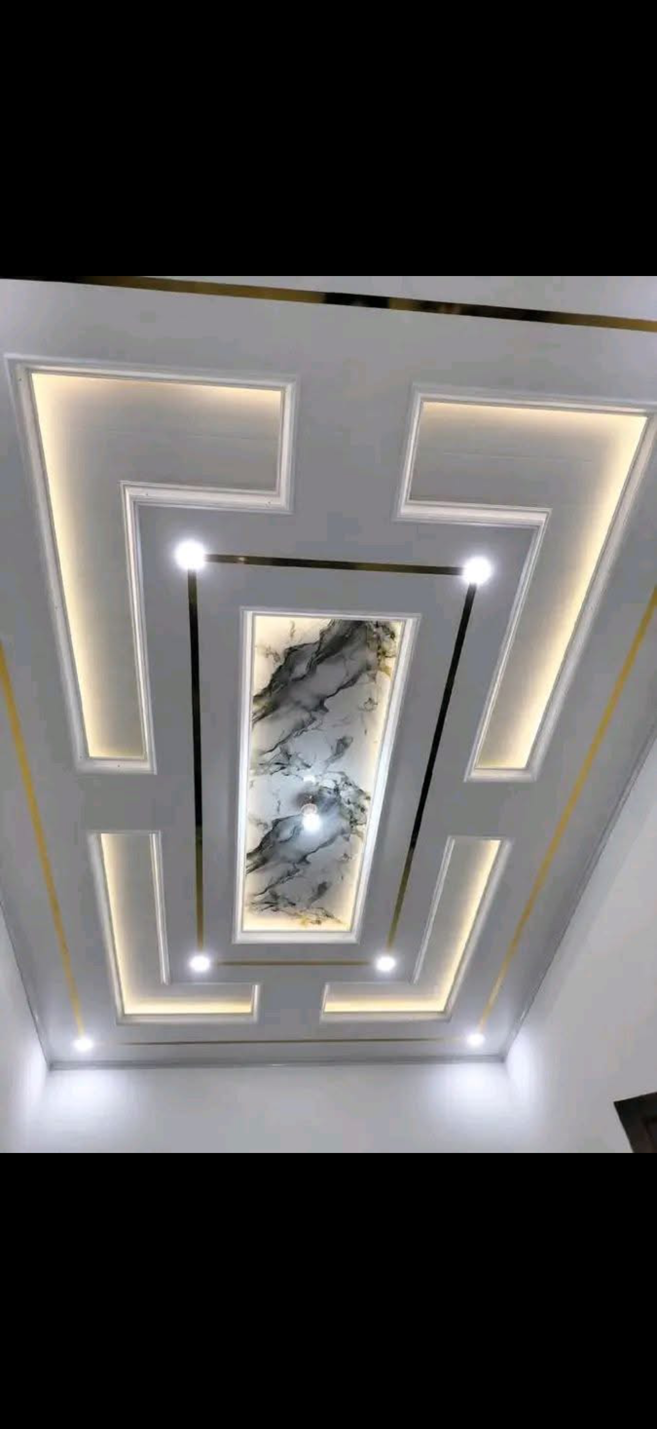 Symmetric coffered drywall ceiling with a Greek-key border, gold trim lines, warm cove lighting and a marble-print center panel