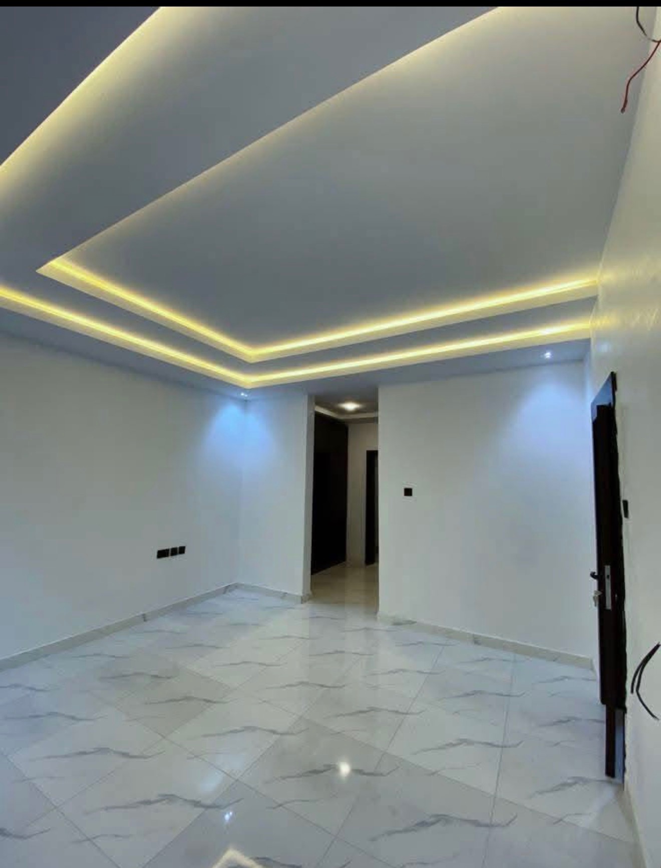 Multi-tier drywall tray ceiling with warm LED cove lighting in a finished room